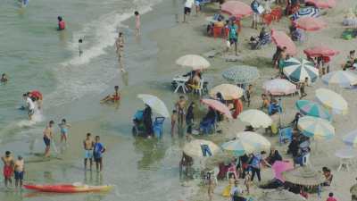 Close-ups of Martil beach and its many swimmers, parasols, pedal boats