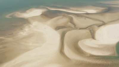 A village built on a sandbar, sand meandering along the seashore