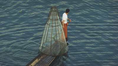 Pêcheur sur une pirogue, immerge son casier